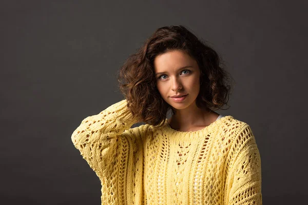 Curly woman in yellow knitted sweater on black background — Stock Photo