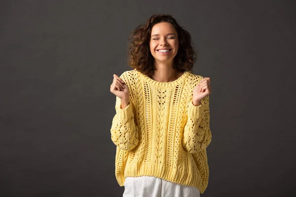 Happy curly woman in yellow knitted sweater on black background — Stock Photo