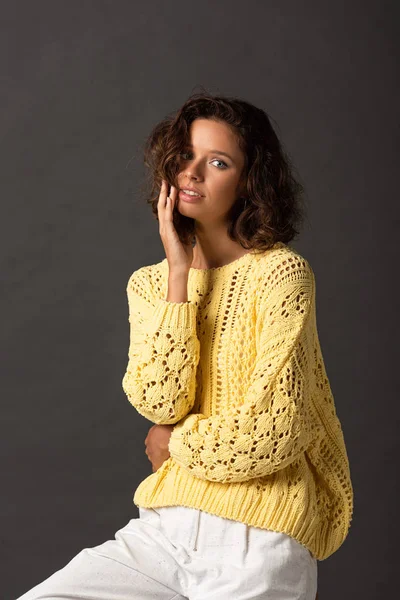 Curly woman in yellow knitted sweater on black background — Stock Photo
