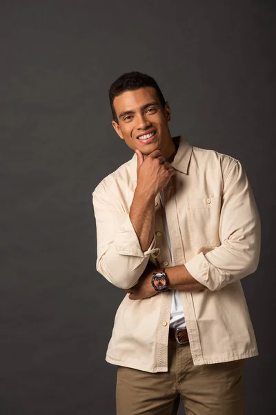 Smiling handsome mixed race man in beige shirt on black background — Stock Photo