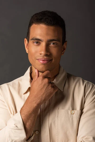 Portrait of smiling handsome mixed race man in beige shirt on black background — Stock Photo