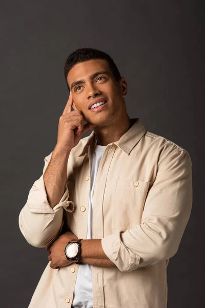 Dreamy handsome mixed race man in beige shirt on black background — Stock Photo