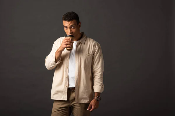 Homme métis en chemise beige buvant du café sur fond noir — Photo de stock