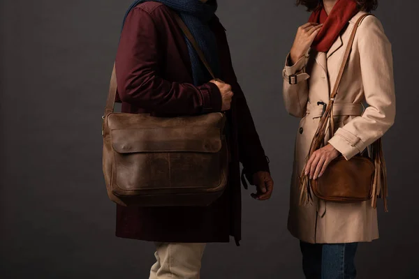 Vista cortada de casal elegante em roupa de outono com sacos no fundo preto — Fotografia de Stock