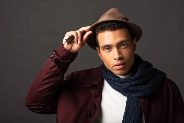 Змішана расова людина в шарфі і капелюсі на чорному тлі — стокове фото