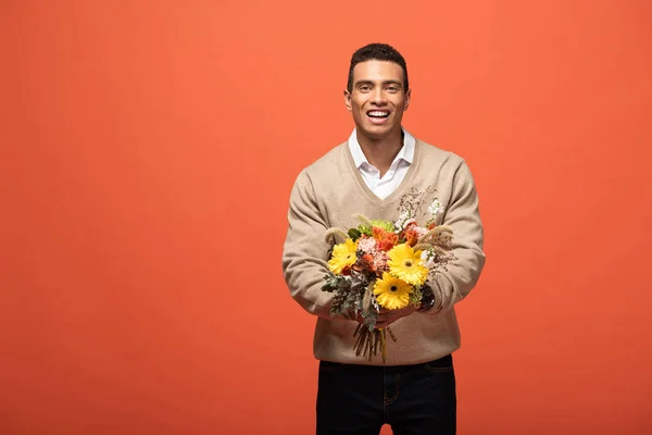 Heureux mixte homme tenant bouquet automnal isolé sur orange — Photo de stock