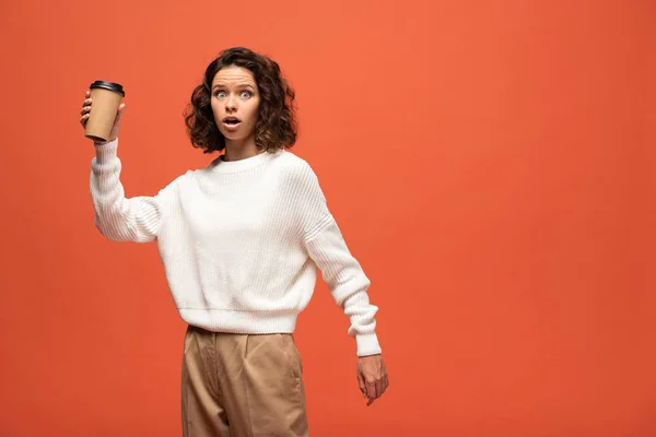 Femme choquée tenant café pour aller isolé sur orange — Photo de stock