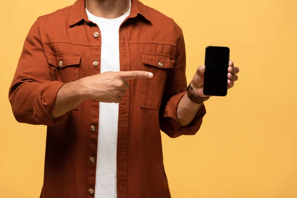 Vista ritagliata di uomo razza mista puntando con il dito verso smartphone con schermo bianco isolato su giallo — Stock Photo