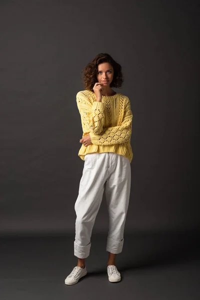 Mujer rizada en suéter amarillo sobre fondo negro - foto de stock