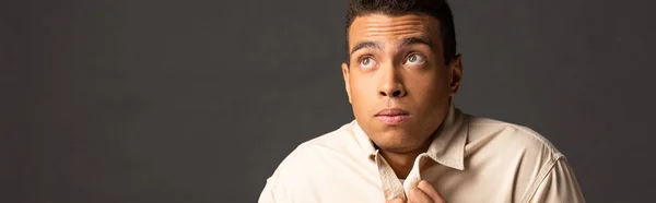 Panoramic shot of handsome mixed race man in beige shirt feeling cold on black background — Stock Photo