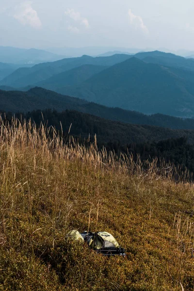 Prato giallo con orzo vicino zaino in montagna contro il cielo — Foto stock