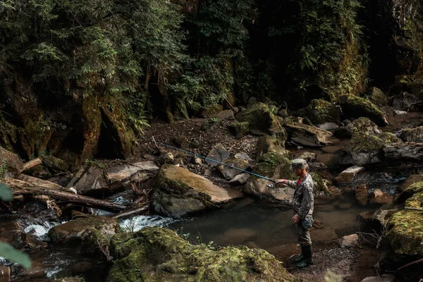 QUIIV, UCRÂNIA - AGOSTO 24, 2019: homem militar em camuflagem pesca uniforme perto do rio que flui em bosques — Fotografia de Stock