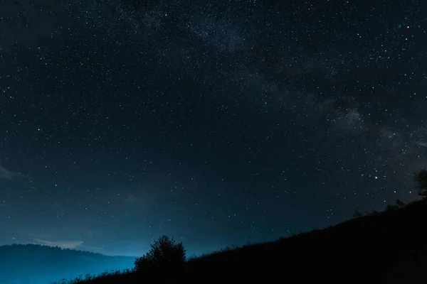 Vía láctea con estrellas brillantes en el cielo azul por la noche - foto de stock