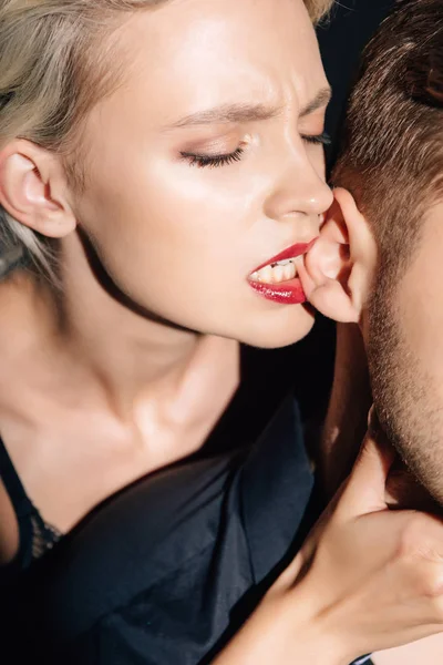 Ausgeschnittene Ansicht einer Frau mit roten Lippen, die dem Mann ins Ohr beißt — Stockfoto