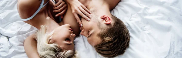 Panoramic shot of attractive woman and handsome man lying on bed — Stock Photo