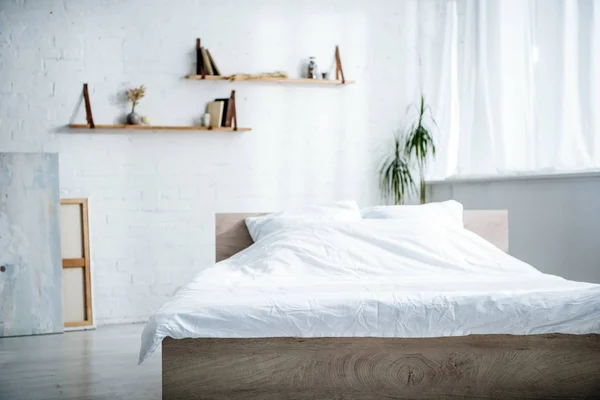 Intérieur de la chambre avec lit, oreillers, couverture, étagères et plantes — Photo de stock