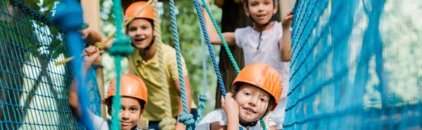 Panoramic shot of happy multicultural climbers in helmets — Stock Photo