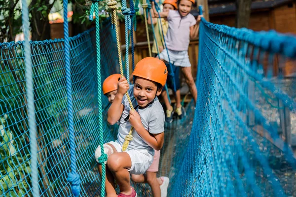 Messa a fuoco selettiva del bambino afro-americano sorridente in casco arrampicata con gli amici — Foto stock