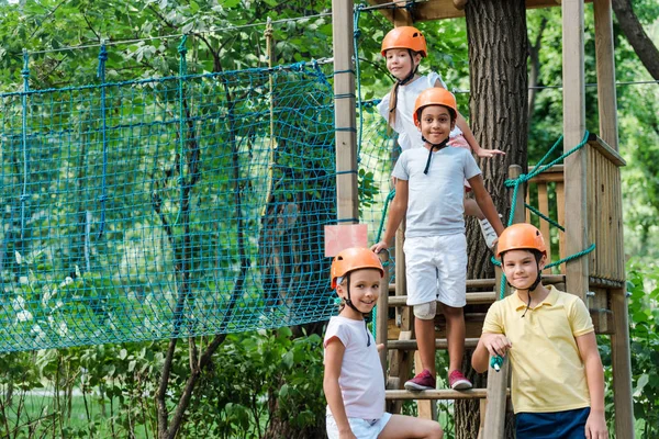 Enfants multiculturels mignons dans les casques regardant la caméra dans le parc d'aventure — Photo de stock