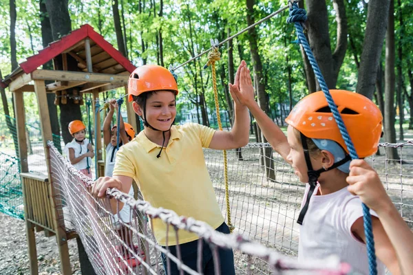 Enfoque selectivo de niño feliz dando choca los cinco a un amigo en el casco - foto de stock