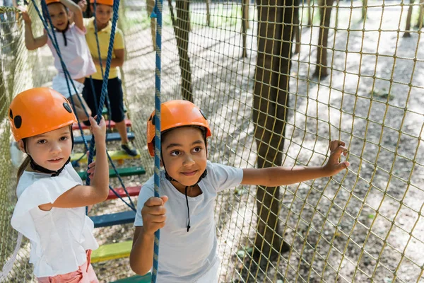 Focus selettivo di amici multiculturali nei caschi arancioni — Foto stock