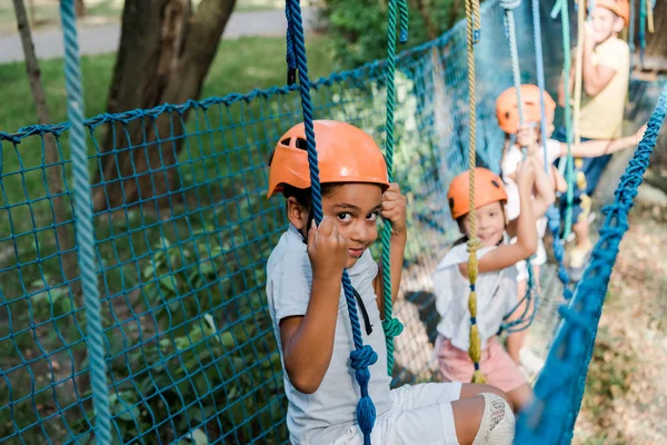 Selektiver Fokus süßer afrikanisch-amerikanischer Kinder in der Nähe glücklicher Freunde in Helmen — Stockfoto