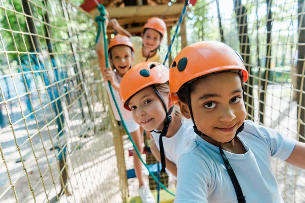 Selektiver Fokus des fröhlichen afrikanisch-amerikanischen Jungen in der Nähe glücklicher Freunde in Helmen — Stockfoto