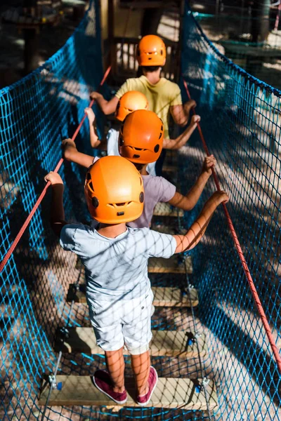 Back view of four multicultural kids in helmets in adventure park — Stock Photo