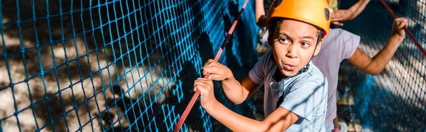 Panoramic shot of african american boy on high rope trail with friends — Stock Photo