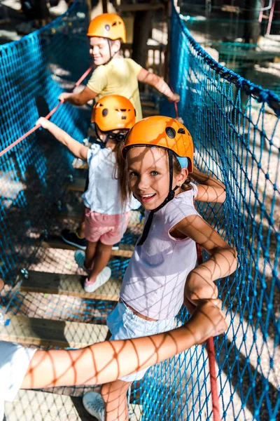 Selective focus of happy and cute kid on high rope trail with friends — Stock Photo
