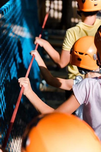 Vista cortada de crianças em capacetes laranja no parque de aventura — Fotografia de Stock