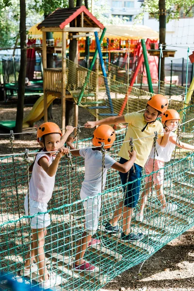 Милые мультикультурные дети в шлемах рядом с красочной деревянной конструкцией — стоковое фото