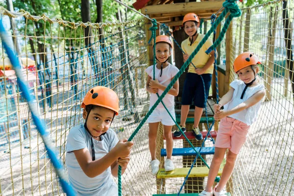 Focus selettivo dei bambini multiculturali nel parco avventura in un percorso ad alta fune — Foto stock
