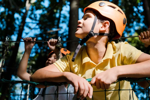 Foco seletivo do menino bonito no capacete laranja perto de amigos — Fotografia de Stock