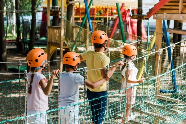 Bonito crianças multiétnicas em capacetes laranja no trem de corda alta — Fotografia de Stock