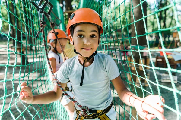 Enfoque selectivo de niño afroamericano lindo cerca de amigo en el casco - foto de stock