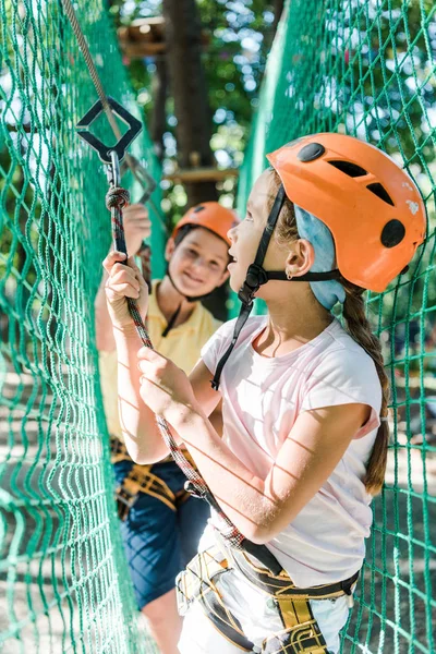 Enfoque selectivo de niños adorables en cascos con equipo de altura en el parque de aventuras - foto de stock