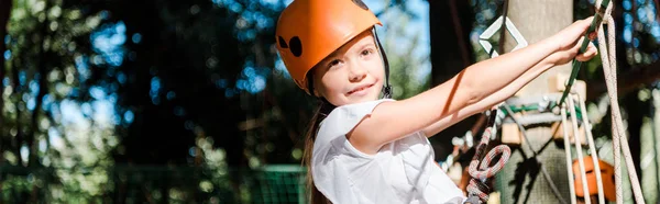 Panoramic shot of positive kid with height equipment on high rope trail — Stock Photo