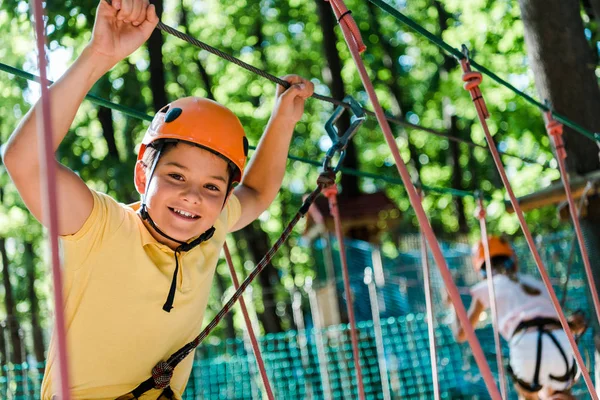 Messa a fuoco selettiva di adorabile bambino in casco con attrezzature di altezza nel parco avventura — Foto stock