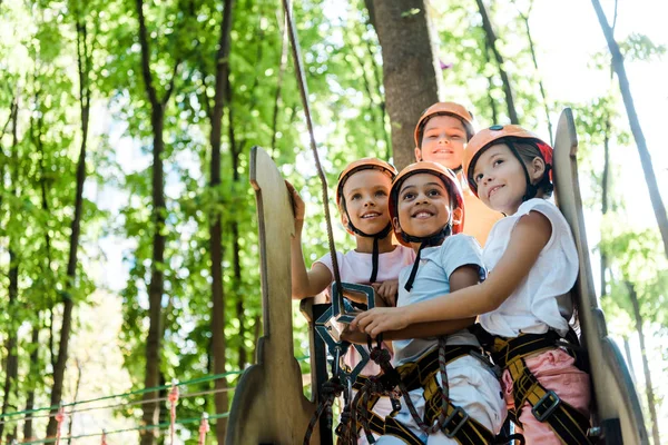 Cheerful multicultural kids looking up in adventure park outside — Stock Photo