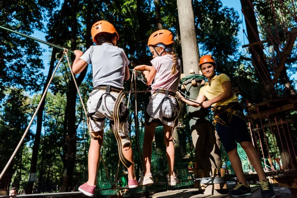 Chicos multiculturales en cascos cerca de amigo en el sendero de cuerda alta - foto de stock