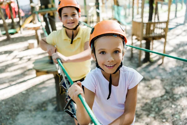 Selective focus of adorable kid in helmet near friend with height equipment in adventure park — Stock Photo