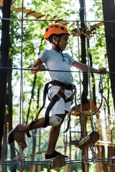 Heureux enfant afro-américain en casque orange dans le parc d'aventure — Photo de stock