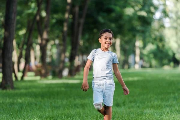 Joyeux garçon afro-américain sur herbe verte dans le parc — Photo de stock