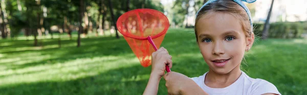 Plan panoramique de l'enfant heureux tenant filet papillon à l'extérieur — Photo de stock