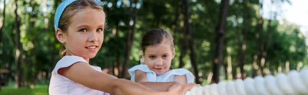 Tiro panorámico de niños lindos compitiendo en tira y afloja fuera - foto de stock