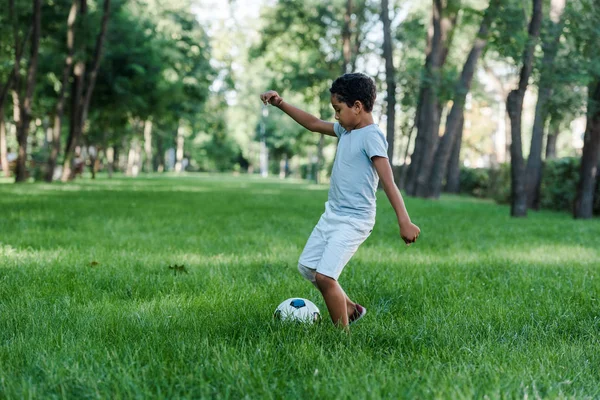 Adorable enfant afro-américain jouant au football sur herbe verte — Photo de stock