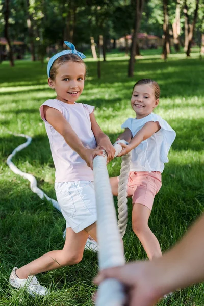 Cropped view of boy competing in tug of war with cute friends — Stock Photo