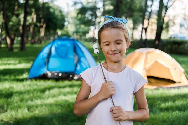 Glückliches Kind lächelt, während es Stock mit süßen Marshmallows hält — Stockfoto