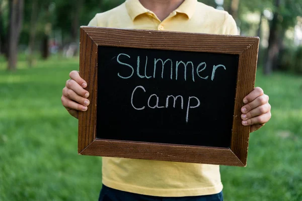 Vue recadrée d'un garçon tenant un tableau à craie avec des lettres de camp d'été — Photo de stock